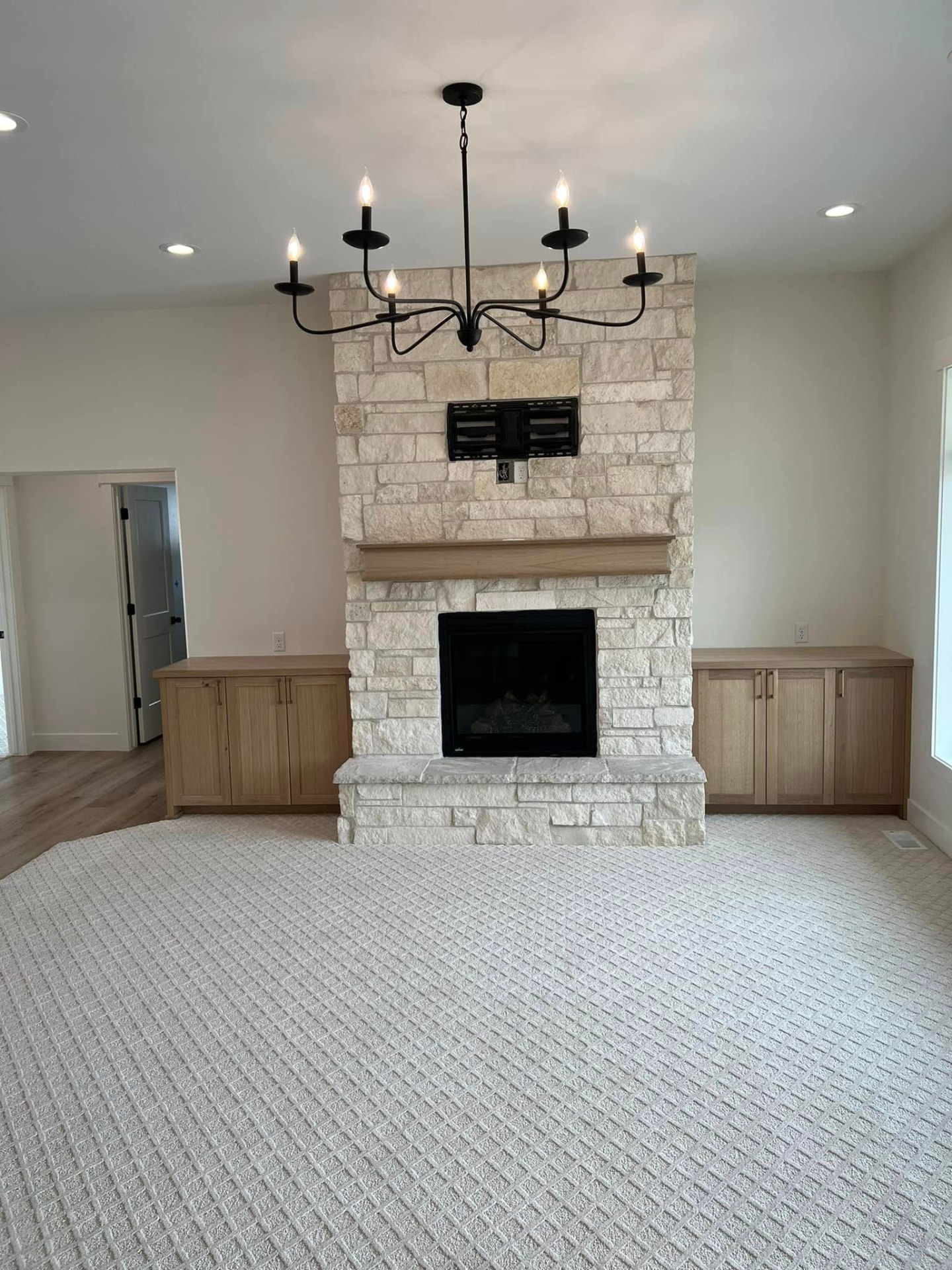 The Martin family room with white stone fireplace and black chandelier