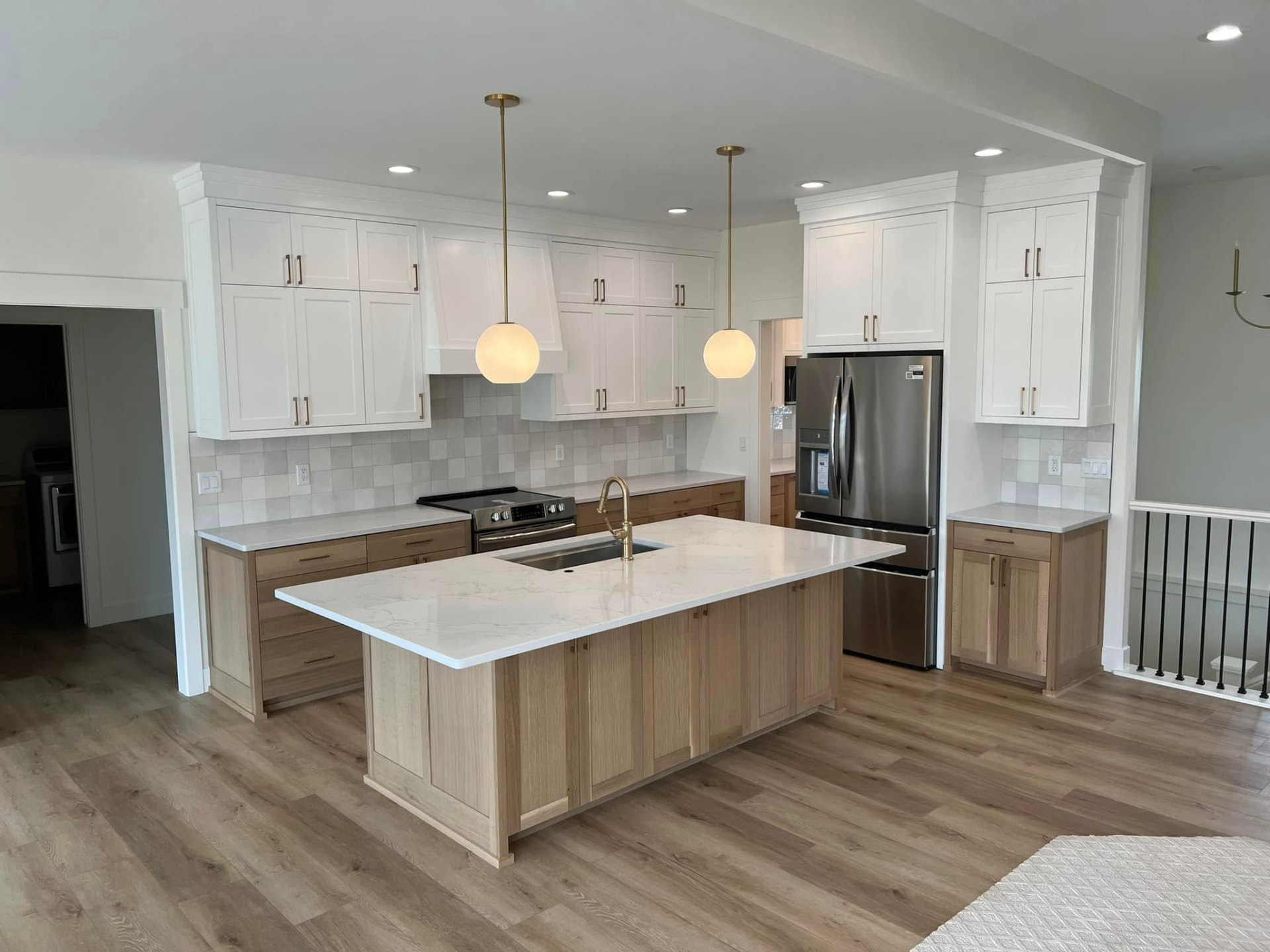 The Martin kitchen with white cabinets, wood island and gold pendants